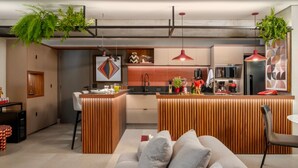 A modern kitchen with a central island, pendant lighting, and a dining area with a sofa and chairs. - Flat de 100m2 com Serviço de Camareira (Sao Paulo)