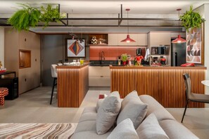 Eine moderne Küche mit einer zentralen Kochinsel, Pendelleuchten und einem Essbereich mit einer Couch und Stühlen.