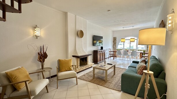 Uma sala de estar com lareira, um espaço de jantar e um sofá verde.