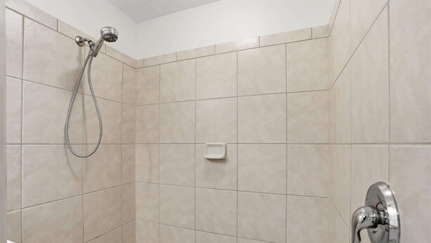 A shower area with a handheld showerhead, a wall-mounted faucet, and a soap dish. - #215 - First Floor - Sleeps 4- Landscape View (Naples)