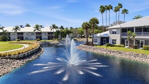 A water feature with a fountain, surrounded by a landscaped area with palm trees and a building with a balcony. - #215 - First Floor - Sleeps 4- Landscape View (Naples)
