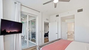 A bedroom with a bed, a TV on the wall, a ceiling fan, and a sliding glass door leading to a balcony. - #215 - First Floor - Sleeps 4- Landscape View (Naples)