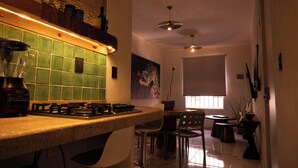 A kitchen with a gas stove, a green tiled backsplash, a dining area with a table and chairs, and a large window. - 15min from downtown,20min airport,5min walking cenote corazon & ZAMNA Festival. (Aldea Tulum)