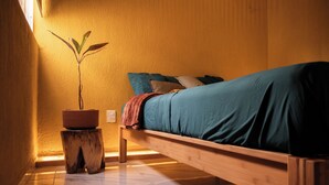 A single bed with a wooden frame, a potted plant, and a small stool. - 15min from downtown,20min airport,5min walking cenote corazon & ZAMNA Festival. (Aldea Tulum)