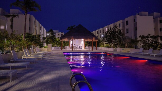 A swimming pool with lounge chairs and a thatched-roof structure. - 15min from downtown,20min airport,5min walking cenote corazon & ZAMNA Festival. (Aldea Tulum)