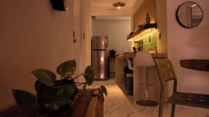 A compact kitchen with a refrigerator, a bar stool, and a potted plant. - 15min from downtown,20min airport,5min walking cenote corazon & ZAMNA Festival. (Aldea Tulum)