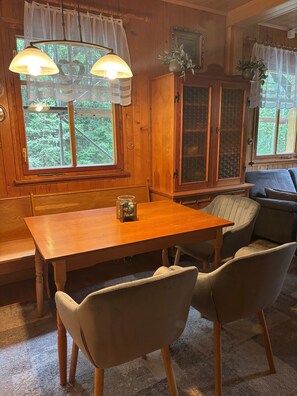 Interior em madeira com mesa de jantar, cadeiras, armário e sofá.