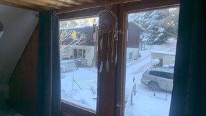A room with a window overlooking a snowy landscape, a hanging dreamcatcher, and a view of a parked car. - Vacation with Dog – Holiday Home for up to 5 Guests (Friedrichroda)