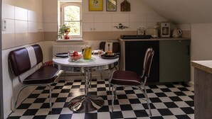 A kitchen with a checkered floor, a dining table with chairs, a window, and a refrigerator. - Nice American Diner Holiday apartment (Penig)