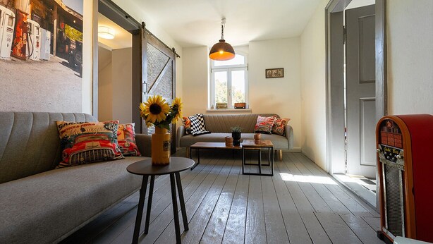 A cozy living room with a sofa, coffee table, and a vintage radio. - Nice American Diner Holiday apartment (Penig)