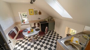 A compact kitchen with a checkered floor, a dining table with chairs, a small island, and a window with a view. - Nice American Diner Holiday apartment (Penig)