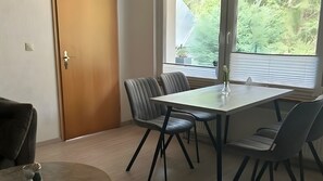 Un coin repas comprenant une table, quatre chaises, un vase et une porte.