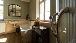 Une salle de bain avec une baignoire, un lavabo, un miroir et une fenêtre.