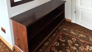 Una habitación con un banco de madera oscura, una puerta blanca y un espejo con marco decorativo.