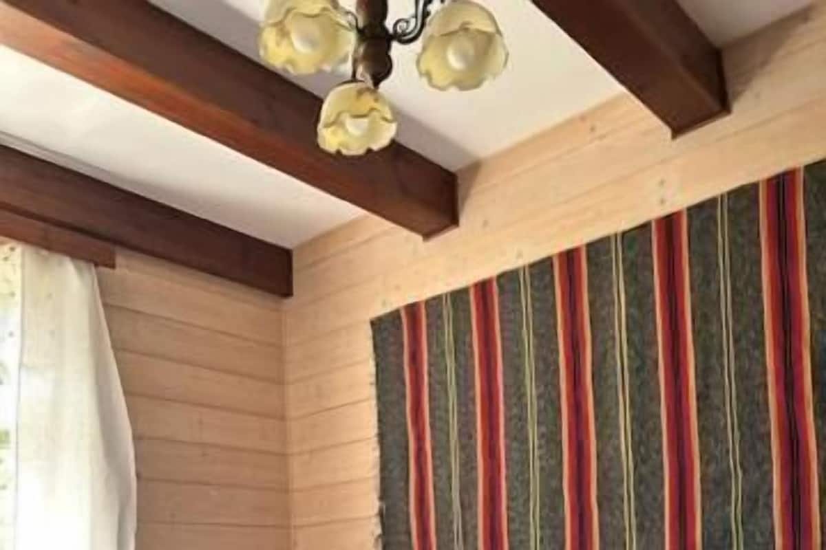 A room with a bed, a window with curtains, a radiator, and a wall with vertical stripes.