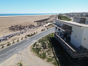 A coastal road with speed limit signs, a beach, and a white building with a balcony.