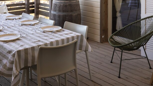 Un'area pranzo all'aperto coperta con un tavolo imbandito per quattro persone, una botte di legno e una sedia.