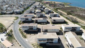 Una zona costiera con numerosi case mobili disposti in file lungo una strada, con spiaggia e oceano sullo sfondo.