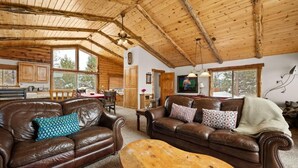 L’intérieur d’un chalet rustique, avec des canapés en cuir, une table basse en bois et un coin repas.