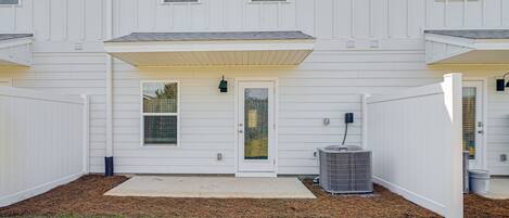 A two-story building with a front porch, a garage door, and a small front yard with grass and mulch.