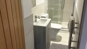Een kleine badkamer met douche, wastafel en toilet.