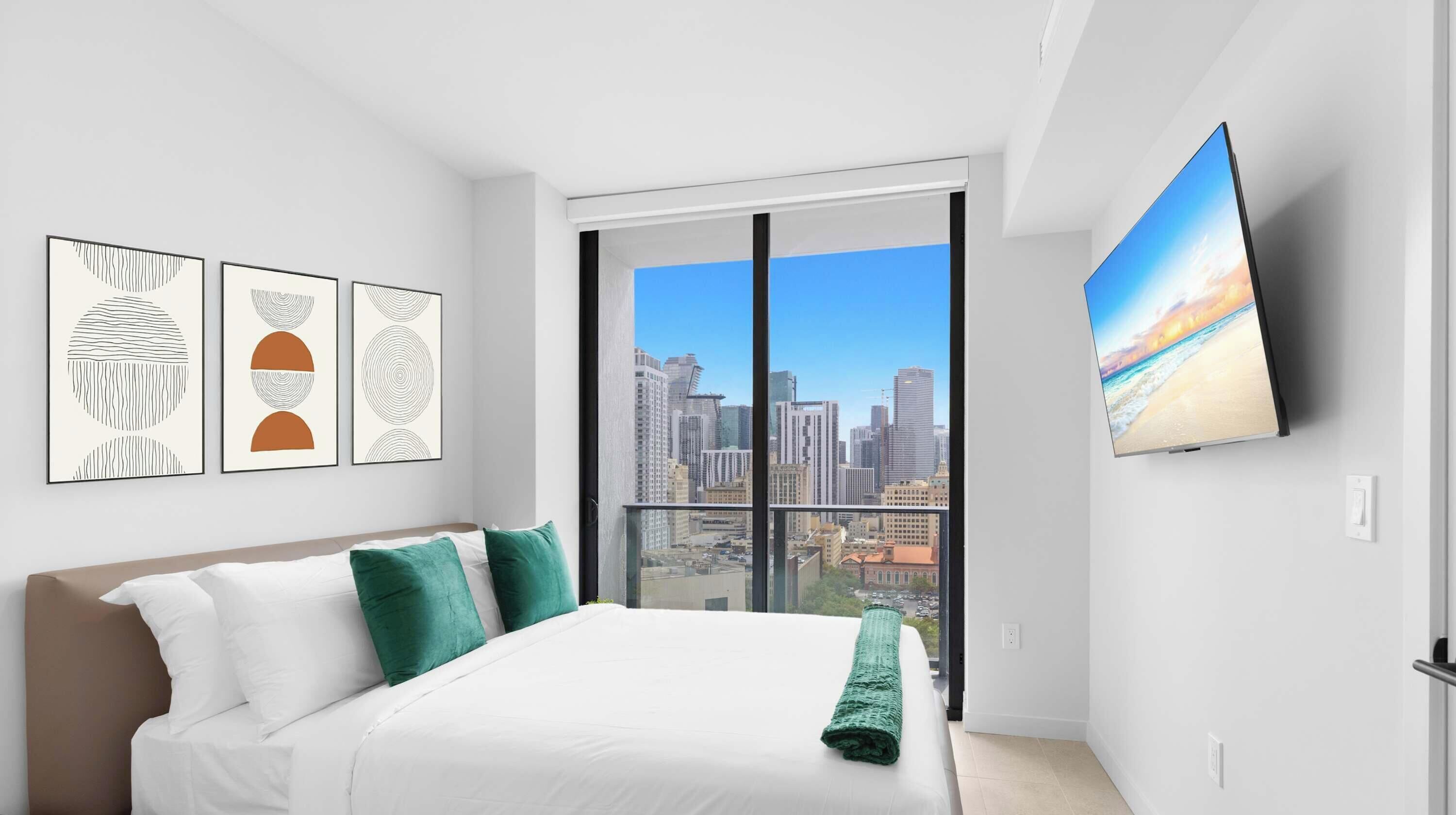 Quarto moderno com cama, almofadas verdes, vista da cidade e televisão na parede.