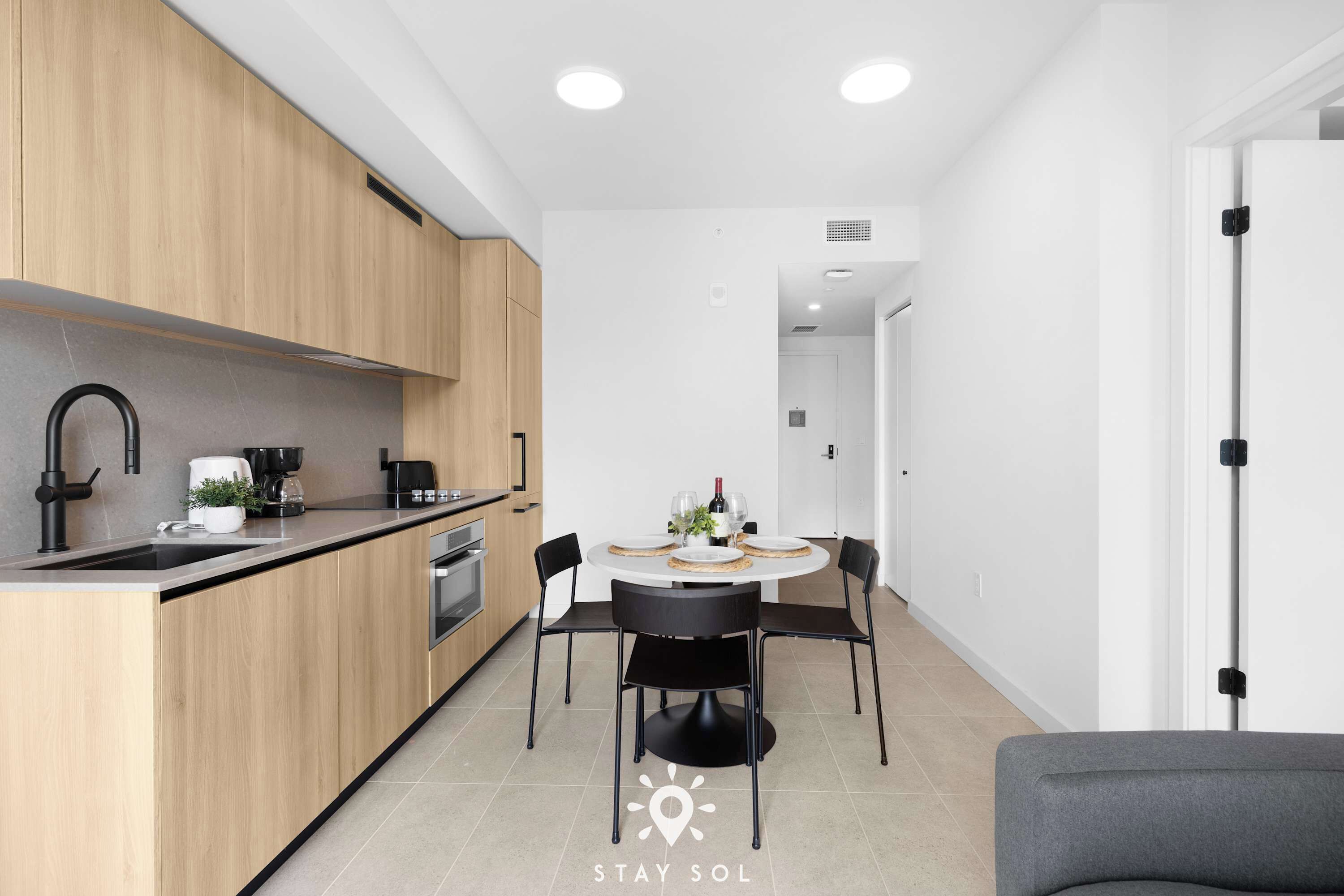 Eine moderne Küche mit Holzausstattung, einer Spüle und einem Essbereich mit rundem Tisch und Stühlen.