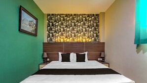 Una habitación de hotel con una cama, dos mesitas de noche, una lámpara de pared y un cuadro en la pared.