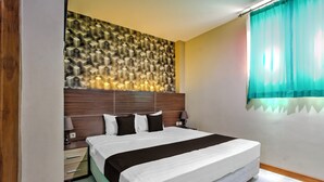 Una habitación de hotel con una cama grande, cabecero de madera, mesitas de noche y un papel tapiz estampado.