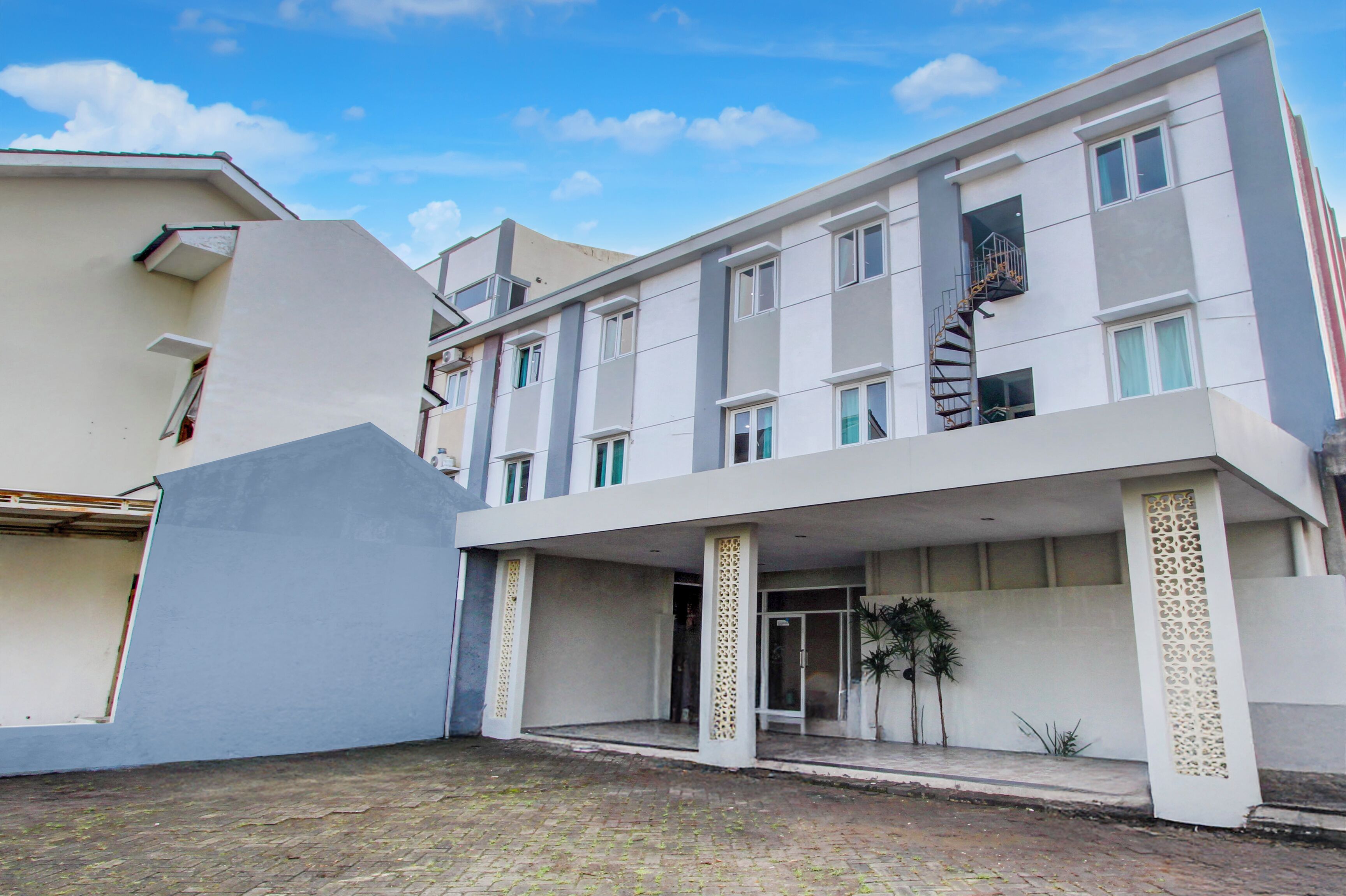 Un edificio moderno con techo plano, múltiples ventanas y una entrada central con galería cubierta.