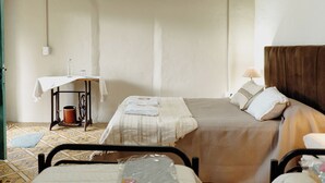 A room with two beds, a small table with a lamp, and a chair. - Serrano Lodging in the Sierras of Córdoba (Achiras)