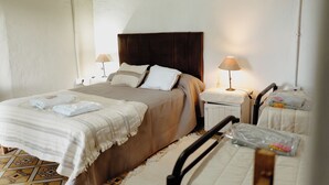 A bedroom with a bed, two bedside tables, a nightstand, a chair, and a window. - Serrano Lodging in the Sierras of Córdoba (Achiras)