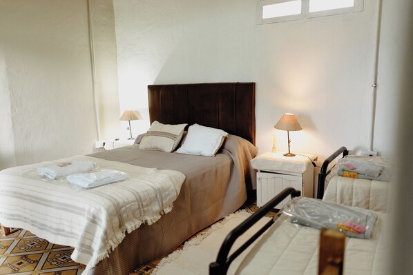 A bedroom with a bed, two bedside tables, a nightstand, a chair, and a window.