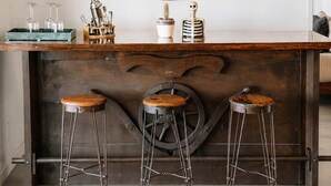Eine Bar mit einem großen dekorativen Spiegel, Hockern und Barutensilien.