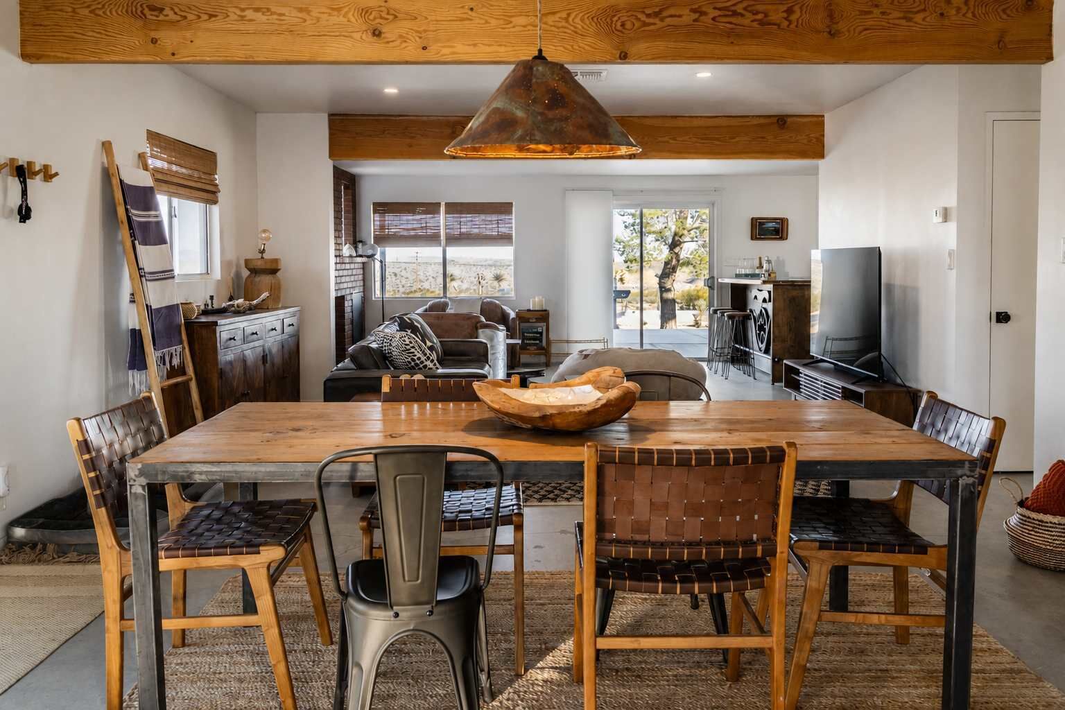 A spacious dining area with a large wooden table, multiple chairs, and a hanging light fixture.