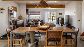 A spacious dining area with a large wooden table, multiple chairs, and a hanging light fixture.