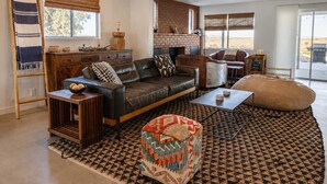 Ein Wohnzimmer mit einer Ledersofa, einem Couchtisch, einem gemusterten Teppich und einem Kamin.
