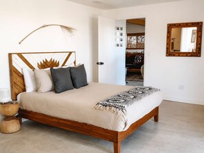 A bed with a wooden frame, a beige bedspread, and a patterned throw. - Lakeview Lodge • Remote Escape, 5-Acres, Pool, Spa (Joshua Tree)