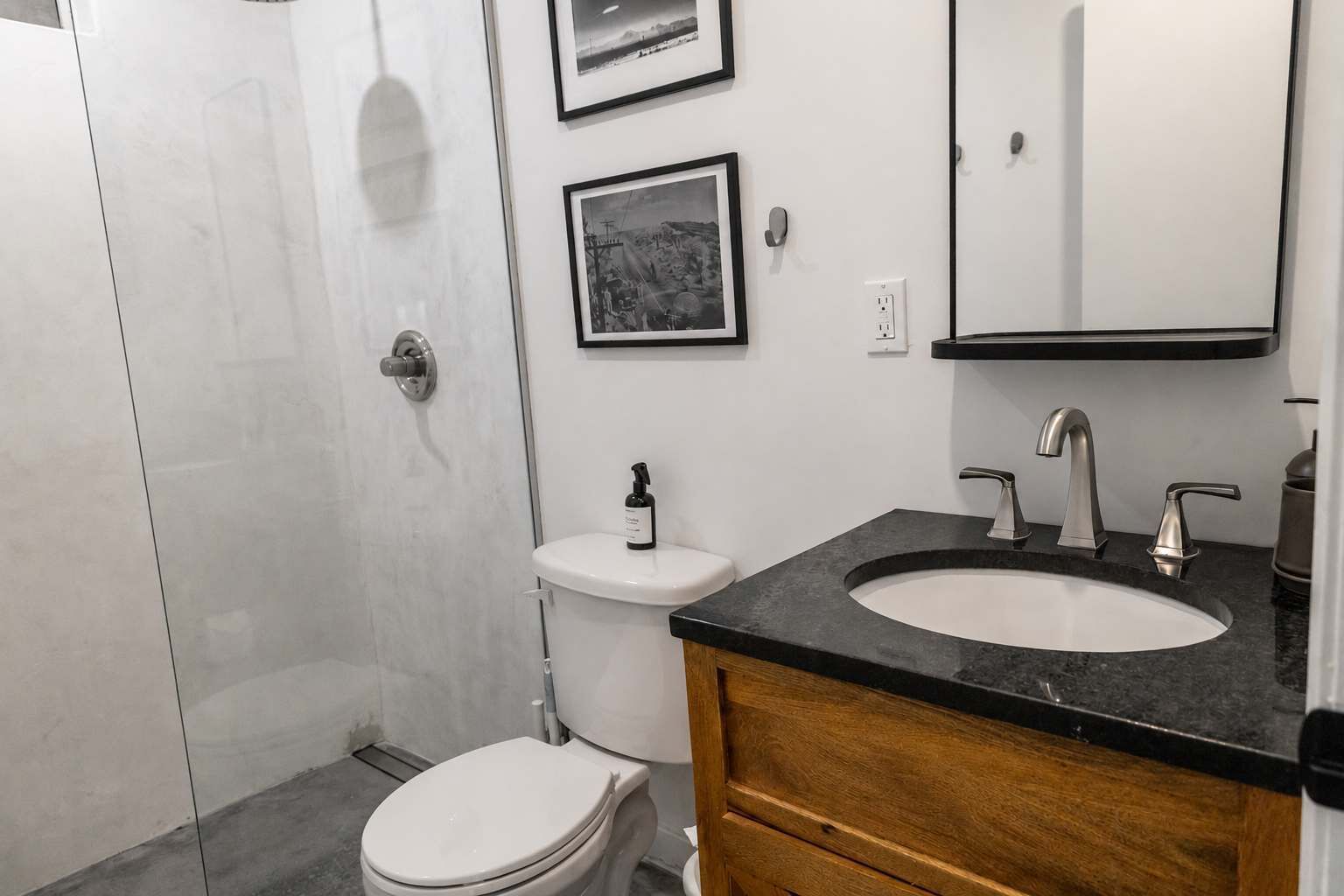A modern bathroom with a toilet, sink, and mirror.