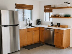 A modern kitchen with stainless steel appliances, wooden cabinets, and a coffee maker. - Lakeview Lodge • Remote Escape, 5-Acres, Pool, Spa (Joshua Tree)