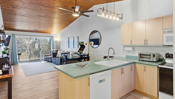A modern kitchen with a dishwasher, microwave, and a dining area with a table and chairs. - Branson Breeze Escape (Branson)