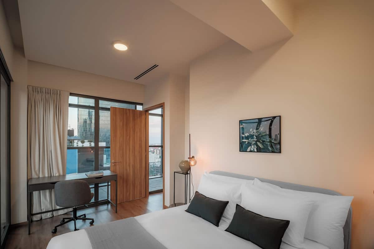 Una habitación de hotel moderna con una cama grande, un escritorio y vistas a la ciudad desde la ventana.