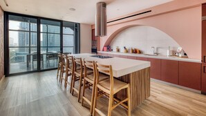 A modern kitchen with a large island, wooden chairs, and a view of the city through large windows. - Nido Reforma (Mexico City)