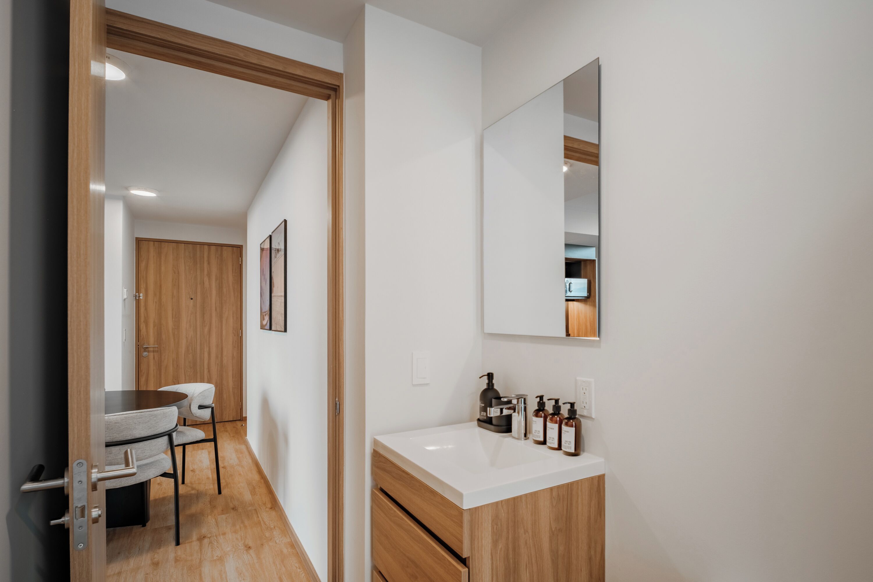 A modern bathroom with a white vanity, wooden cabinets, and a mirror.
