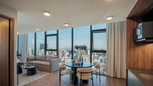 A modern living room with a large window, a round dining table, and a sofa. - Nido Reforma (Mexico City)