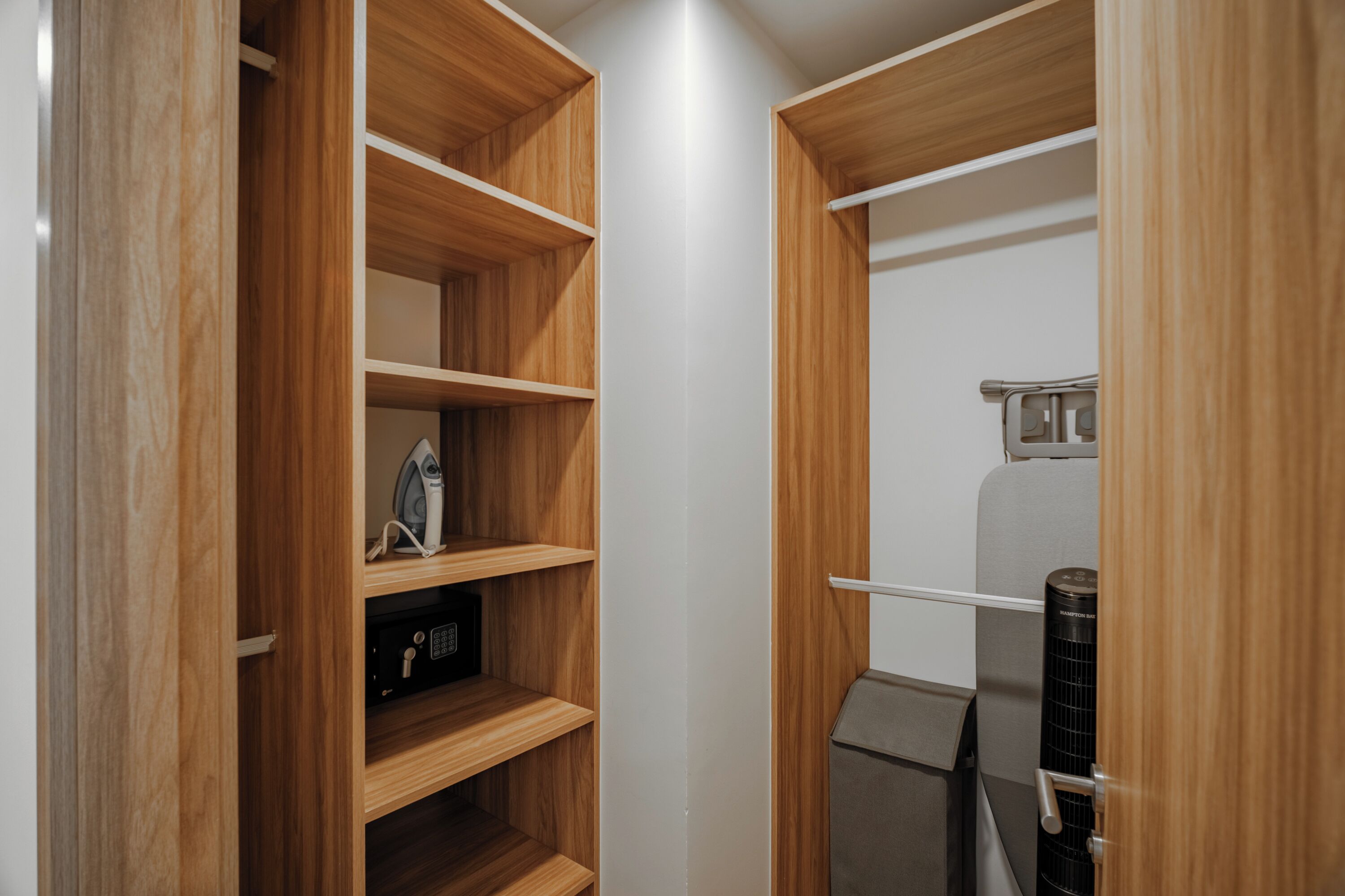 Un placard en bois avec des étagères, une tringle et un petit appareil électroménager.