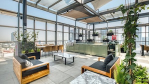 A rooftop lounge with seating, a kitchen area, and potted plants. - Nido Reforma (Mexico City)
