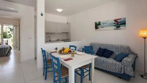 Un comedor con una mesa blanca y sillas azules, un sofá estampado y un cuadro en la pared.