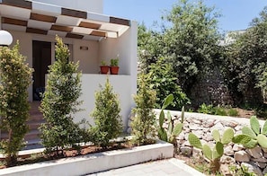 A modern building with a checkered roof, a stone wall, and various plants including cacti and small trees. - Seaside Studio! 🌴House in the heart of Castro, just a 15 min walk from the sea (Castro)