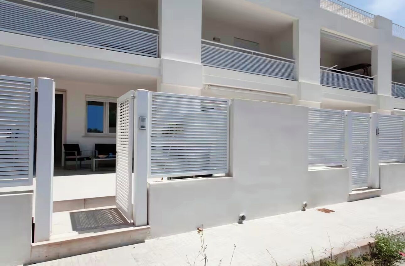 Un edificio moderno con diversi balconi, pareti esterne bianche e un tetto piatto.